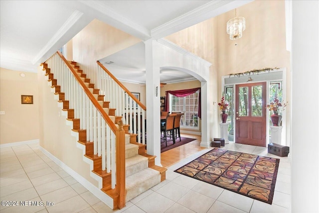 tiled foyer featuring ornamental molding and an inviting chandelier