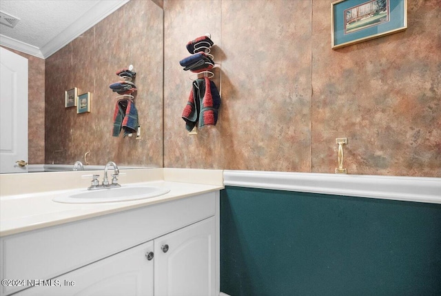 bathroom with a textured ceiling, crown molding, and vanity