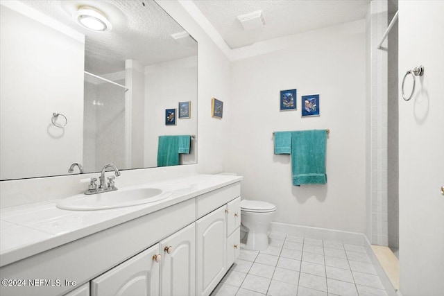 bathroom with tiled shower, vanity, a textured ceiling, toilet, and tile patterned floors