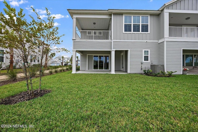 back of house with cooling unit, a balcony, a lawn, and a patio area