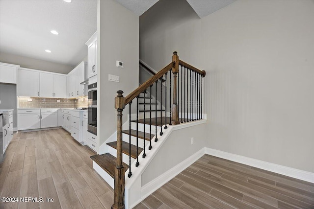 staircase featuring a textured ceiling and wood-type flooring