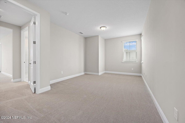 carpeted empty room with a textured ceiling