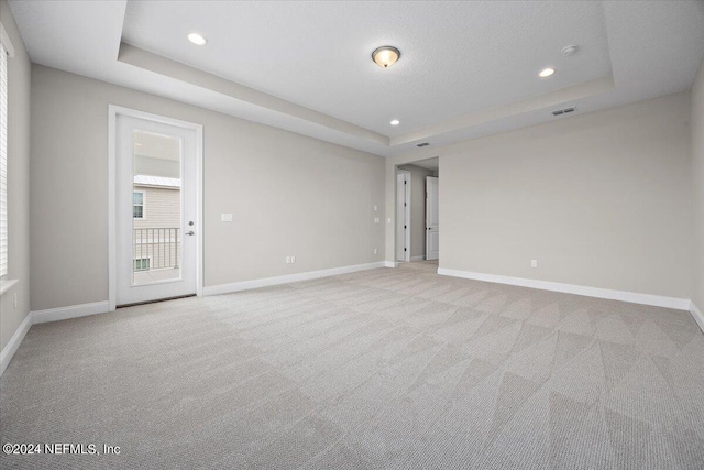 carpeted empty room featuring a tray ceiling