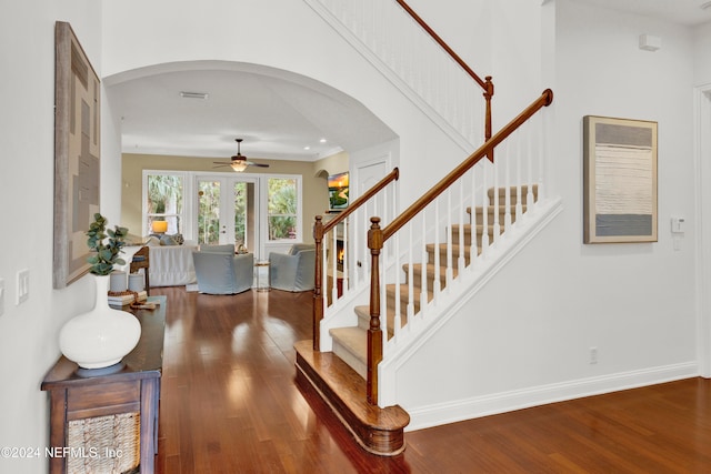 staircase with arched walkways, visible vents, baseboards, and wood finished floors