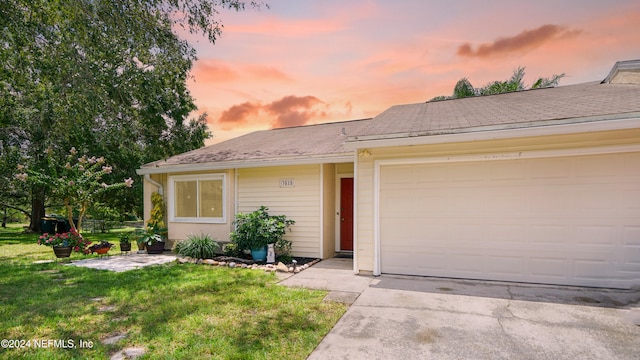 ranch-style home featuring a garage and a yard