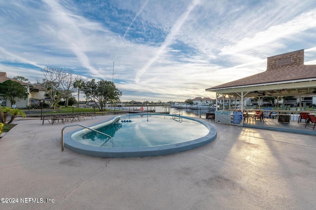 view of swimming pool featuring a patio area and a water view