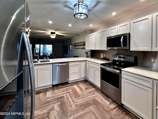 kitchen featuring kitchen peninsula, appliances with stainless steel finishes, dark parquet floors, ceiling fan, and white cabinetry