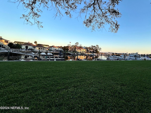 view of home's community featuring a lawn, a water view, and a dock