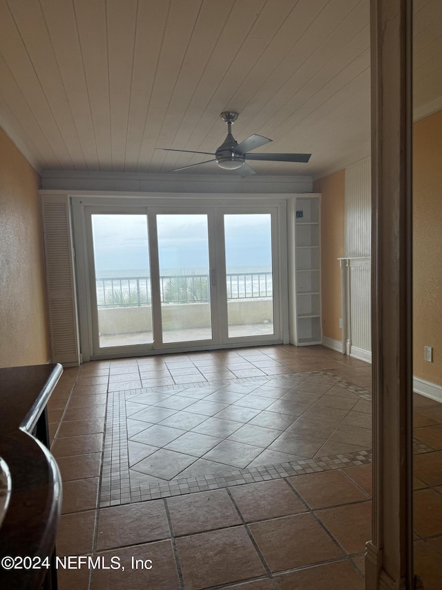 empty room featuring ceiling fan, wood ceiling, and a water view