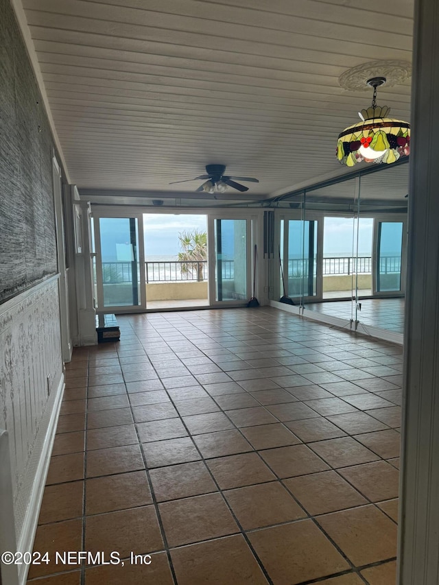 empty room with wood ceiling, ceiling fan, tile patterned floors, and a wealth of natural light