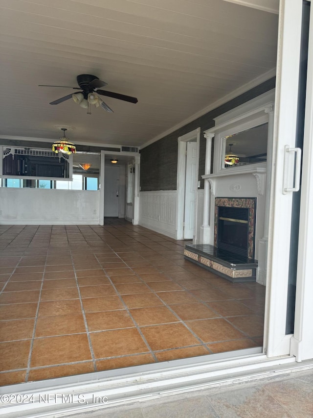 unfurnished living room featuring ornamental molding, a premium fireplace, and ceiling fan