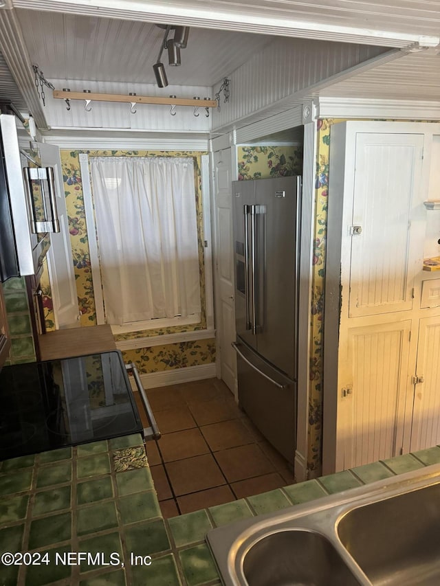 kitchen featuring high end refrigerator, tile patterned flooring, track lighting, and tile countertops