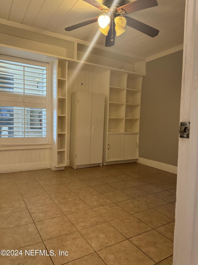 tiled spare room featuring ceiling fan and ornamental molding