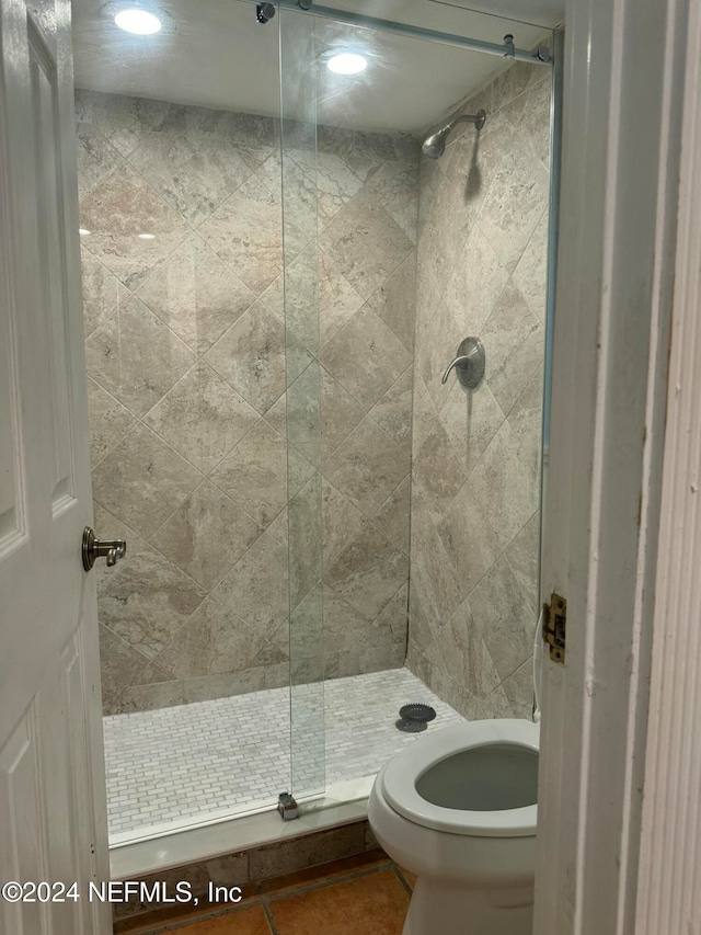 bathroom featuring a tile shower and toilet