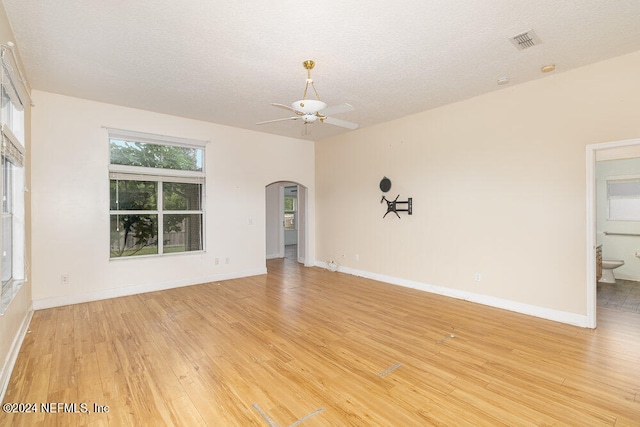 empty room featuring a textured ceiling, light hardwood / wood-style floors, and ceiling fan