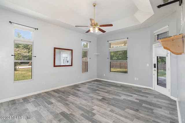 spare room with a tray ceiling, ceiling fan, and dark hardwood / wood-style flooring