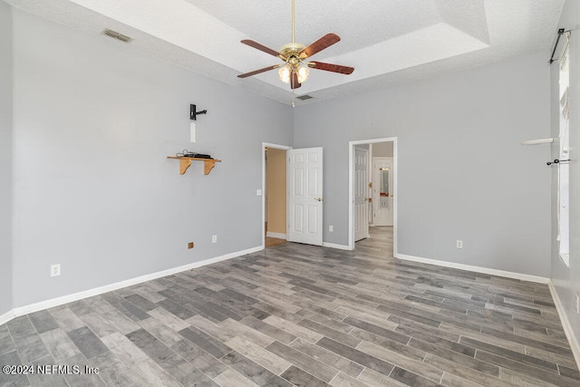 unfurnished bedroom featuring a towering ceiling, a textured ceiling, hardwood / wood-style flooring, and ceiling fan