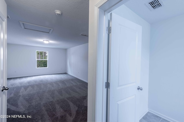 carpeted empty room featuring a textured ceiling