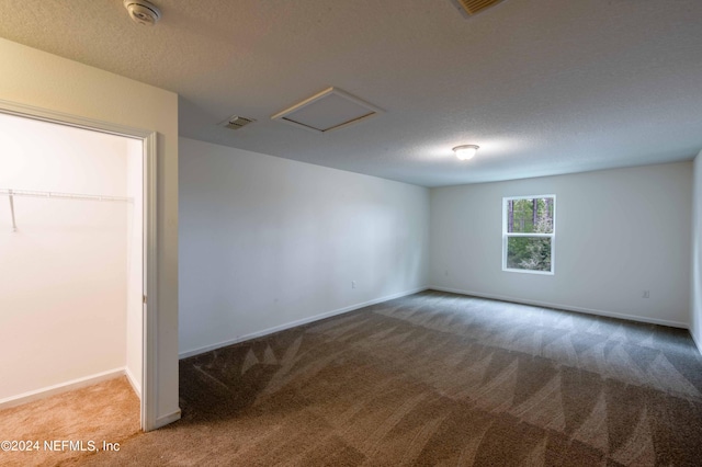 spare room featuring light carpet and a textured ceiling