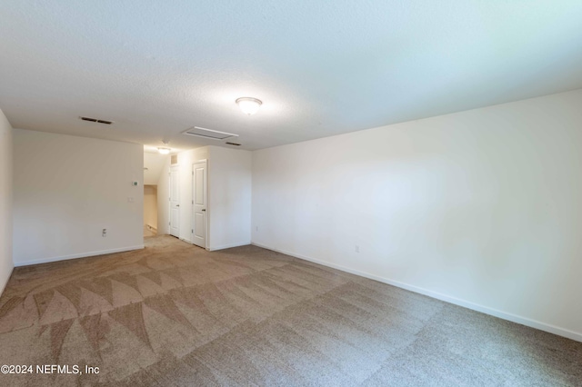 unfurnished room featuring light carpet and a textured ceiling