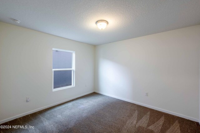 carpeted empty room with a textured ceiling