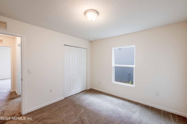 unfurnished bedroom with a textured ceiling, carpet flooring, and a closet