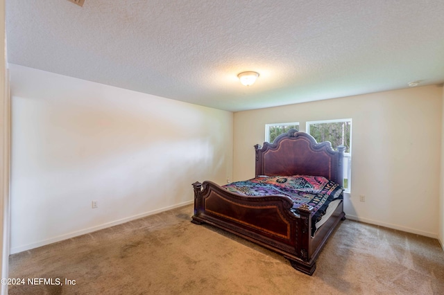 bedroom featuring a textured ceiling and light carpet