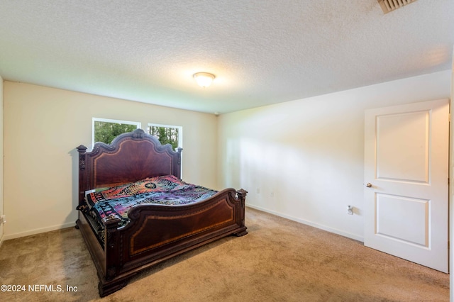 bedroom with a textured ceiling and light carpet