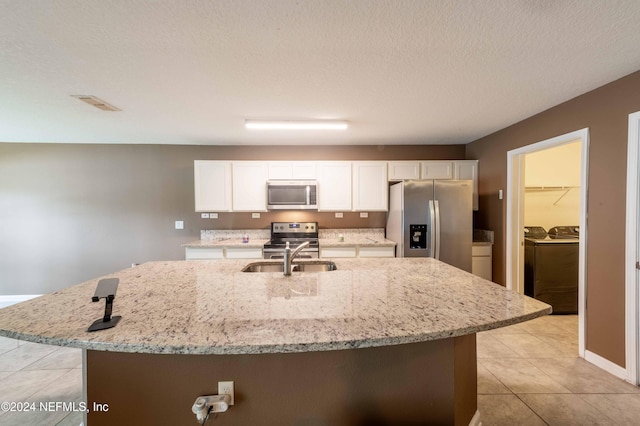 kitchen featuring white cabinetry, separate washer and dryer, stainless steel appliances, a kitchen island with sink, and sink