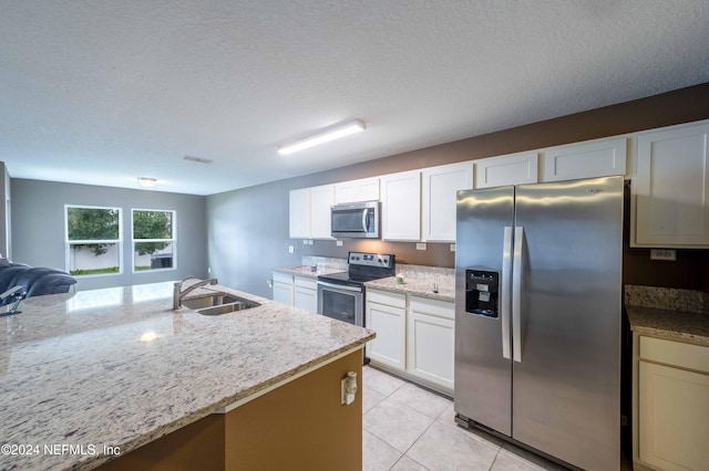 kitchen featuring light stone counters, a textured ceiling, stainless steel appliances, and sink