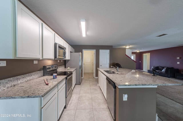 kitchen with sink, white cabinetry, a center island with sink, appliances with stainless steel finishes, and light stone countertops