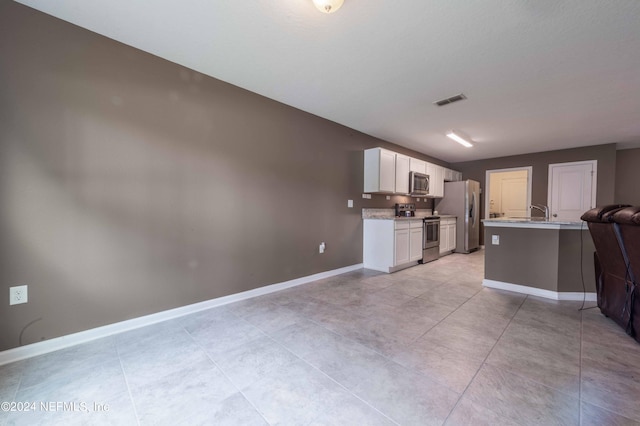 kitchen featuring light stone counters, stainless steel appliances, and white cabinetry