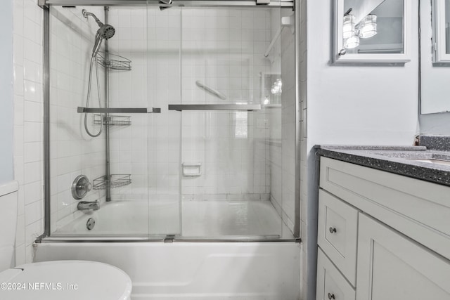 full bathroom with bath / shower combo with glass door, vanity, and toilet