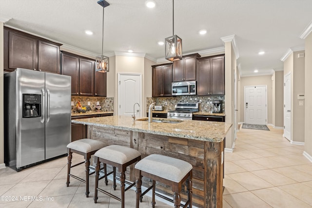 kitchen featuring stainless steel appliances, sink, light tile patterned flooring, dark brown cabinetry, and pendant lighting