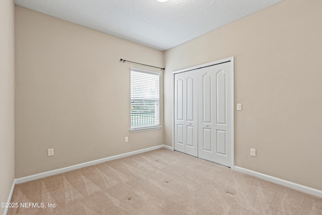 unfurnished bedroom with a textured ceiling, light colored carpet, and a closet