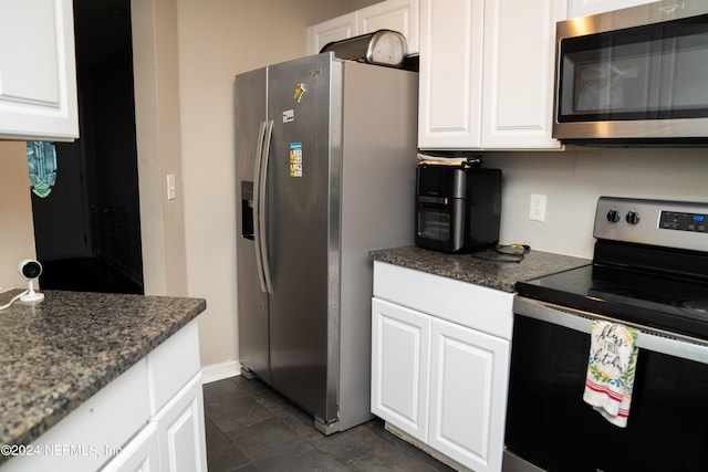 kitchen with dark stone counters, dark tile patterned floors, stainless steel appliances, and white cabinets