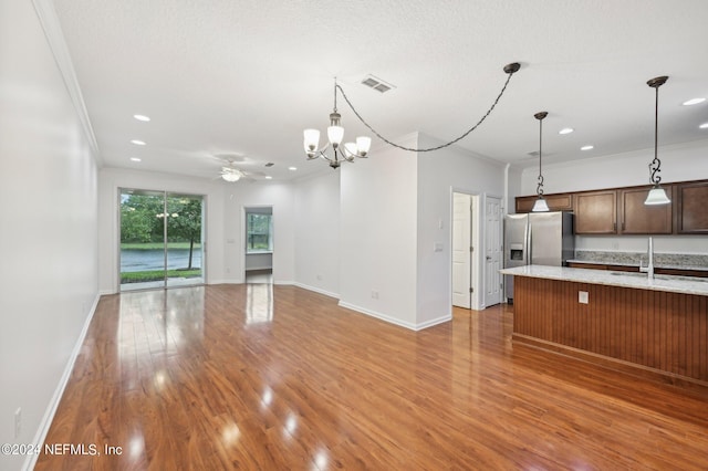 kitchen with ornamental molding, sink, hardwood / wood-style flooring, stainless steel refrigerator with ice dispenser, and light stone countertops