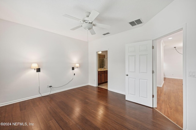 unfurnished bedroom featuring ensuite bath, dark hardwood / wood-style flooring, and ceiling fan