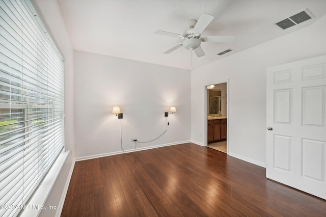 interior space with ceiling fan, ensuite bath, and dark hardwood / wood-style flooring