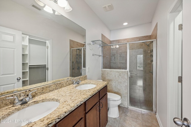 bathroom featuring tile patterned flooring, walk in shower, vanity, and toilet