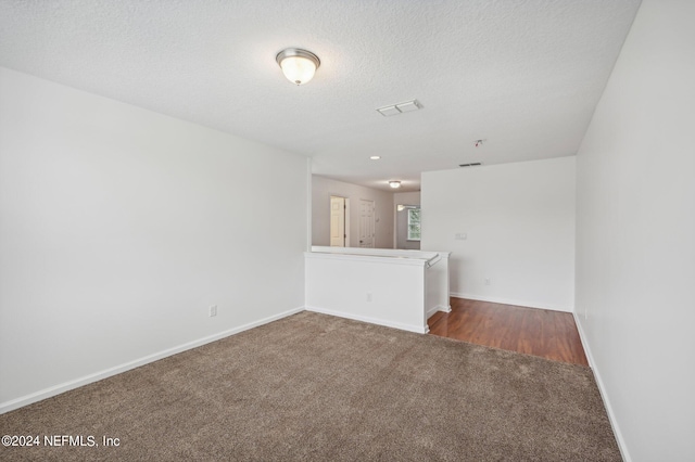 unfurnished living room with dark carpet and a textured ceiling