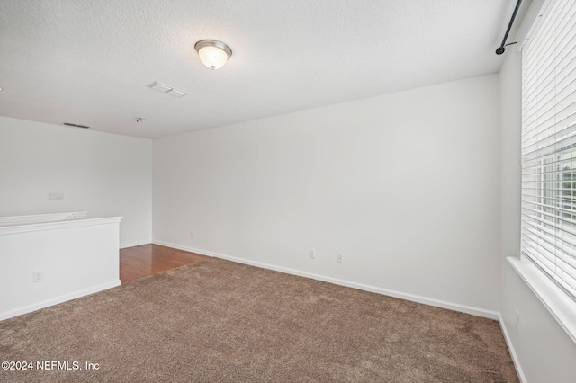 carpeted spare room with a textured ceiling