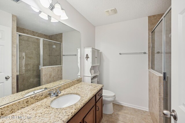 bathroom featuring vanity, a shower with door, toilet, and a textured ceiling