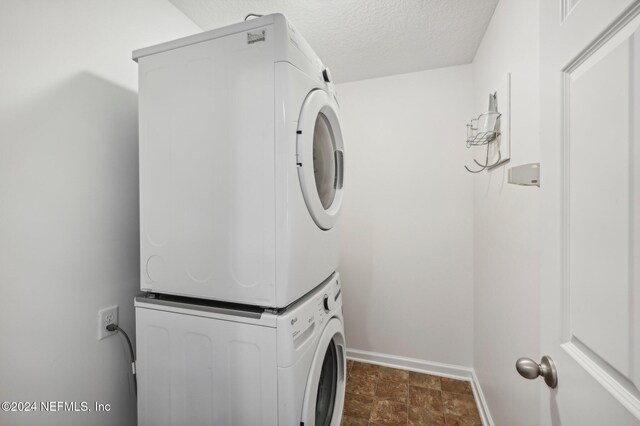 clothes washing area with stacked washer / dryer and a textured ceiling