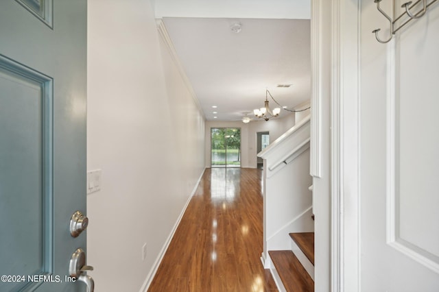 corridor with a notable chandelier, crown molding, and hardwood / wood-style floors