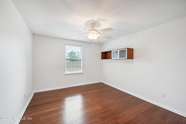 empty room with a textured ceiling, ceiling fan, and dark hardwood / wood-style flooring