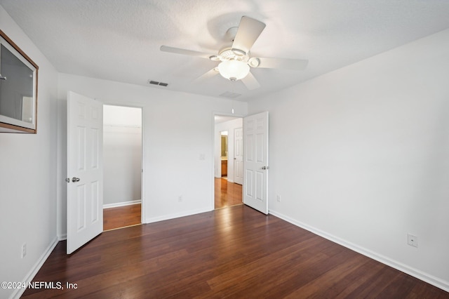 unfurnished bedroom with ceiling fan, a closet, dark hardwood / wood-style floors, and a textured ceiling