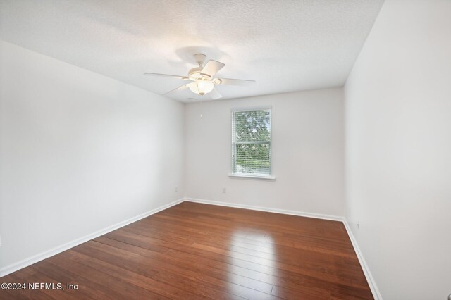 empty room with dark hardwood / wood-style floors, a textured ceiling, and ceiling fan