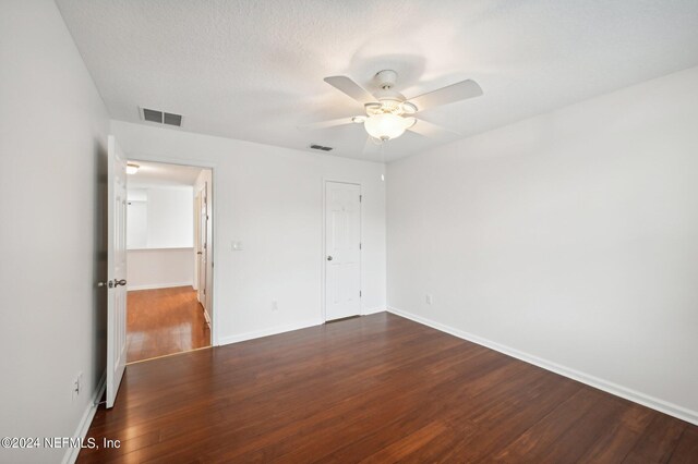 unfurnished bedroom with a textured ceiling, ceiling fan, a closet, and dark hardwood / wood-style flooring