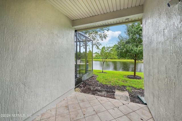 view of patio / terrace featuring a lanai and a water view